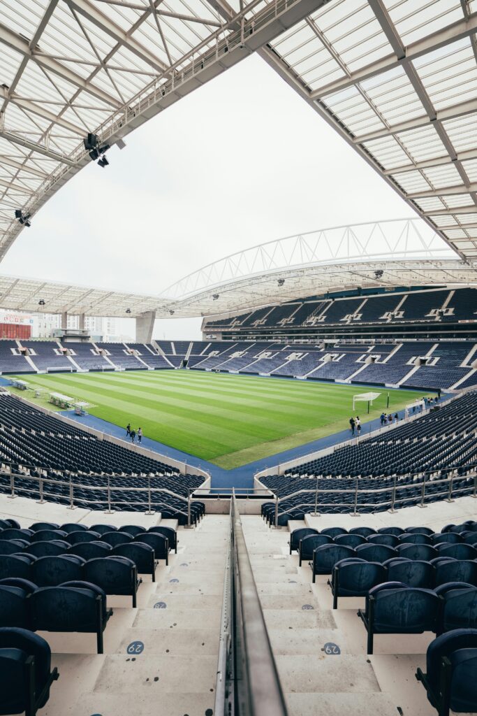Wide-angle view of a contemporary stadium featuring empty bleachers and a well-maintained grass field, perfect for various sports.